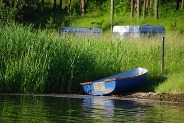 Łódka nad brzegiem jeziora - obrazy, fototapety, plakaty