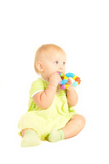 Happy cute baby girl (10 months) sitting on bed and playing with