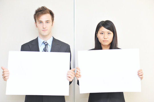 two business person holidng a white board