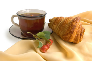 Brown glass cup with tea and croissants