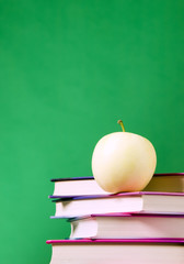 Yellow apple placed on books