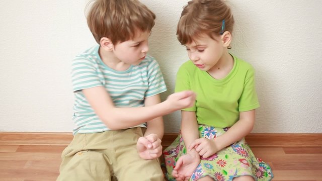 boy and girl sit leaning against wall and looks sores on skin