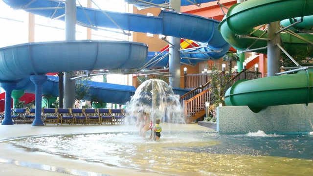 woman and children come under fountain in indoor water park