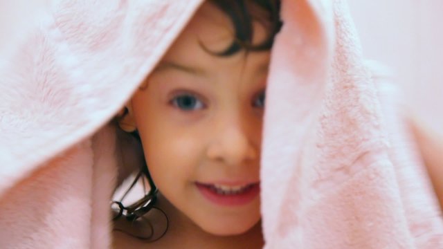 cute happy little girl dries by towel in bathroom