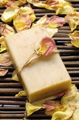 Bowl of soap with rose petals on bamboo mat