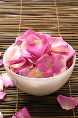 Bowl of rose petals on bamboo mat