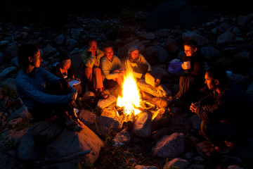 People near campfire in forest. - obrazy, fototapety, plakaty