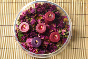 Bowl of dry petals with soap on bamboo mat