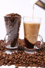 Making of caffe latte:glass of coffee, milk being poured into it