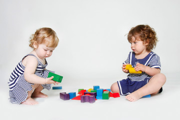 two toddler girls playing with building blocks