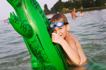 Young boy hold his green floater crocodile in the water
