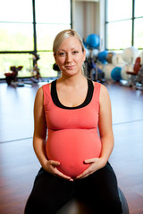 Obraz na płótnie Canvas Pregnant woman sitting on fitness ball holding belly.