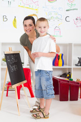 happy young teacher and preschool boy in classroom