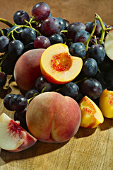 Pfirsiche und frische Weintrauben auf einer Holzplatte