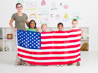 american teacher and preschool students holding flag