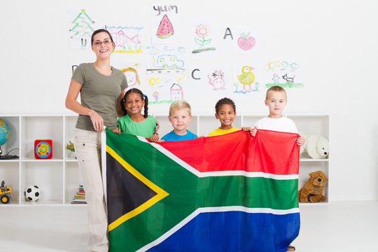 south african teacher and preschool kids holding flag
