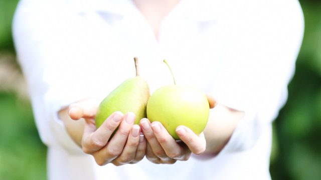 A woman's hands full of green pears