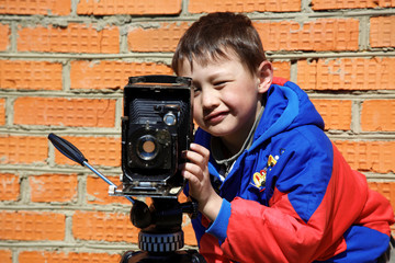 kid making a shot with retro camera on tripod