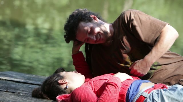 Young couple in love resting face to face on a jetty.
