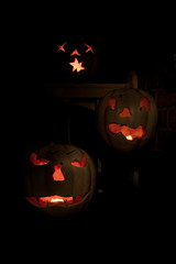 Three lit white jack o-lanterns on a bench