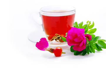 Herbal tea in cup of glass with dog-rose flowers on a white back