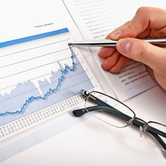 Businessman's hand showing diagram on financial report with pen.