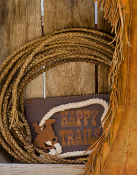 Happy Trails sign, rope and chaps on old wood shelf