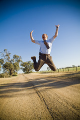 Fototapeta premium Man dressed in shirt and tie leaps into the air in happiness to be out of the office