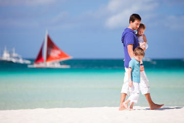 Father and two kids walking along the beach