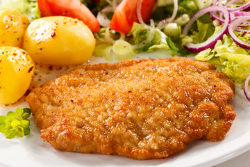 Fried pork chop with potatoes and vegetable salad