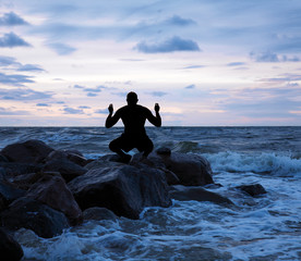 Man meditating on a stony sea shore