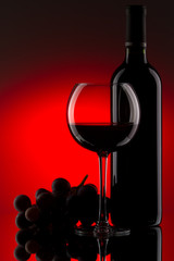 Still-life with the red wine bottle, glass and grapes