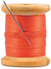Old wooden bobbin with red thread and needle, isolated