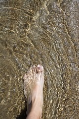 beach tourist feet walking on shore shallow water