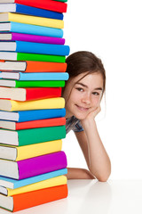 Student sitting behind pile of books on white