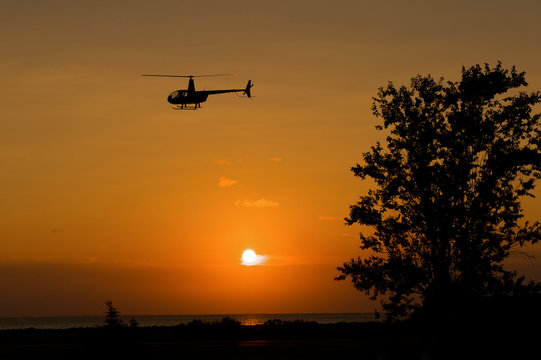 Silhouette of a helicopter from the light of a sunrise.