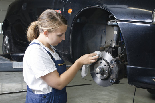 Azubi in der Autowerkstatt reinigt Bremsen