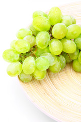 Picture of green grape on wooden plate over white