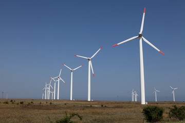 Row of wind turbines against a blue sky