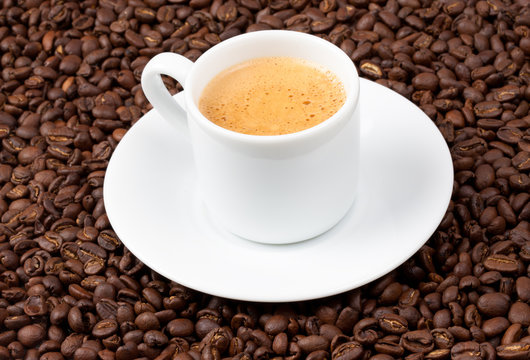 White espresso cup sat on coffee beans © swalwellj