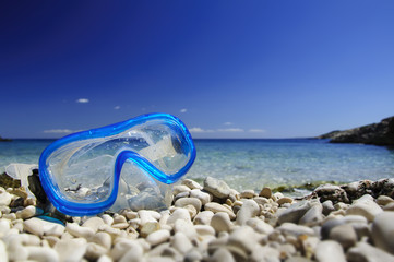 Blue diving mask on pebble beach