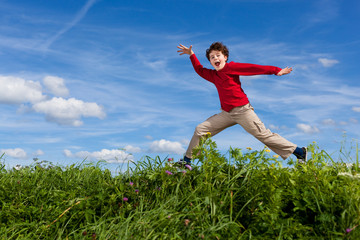 Fototapeta premium Boy jumping, running against blue sky
