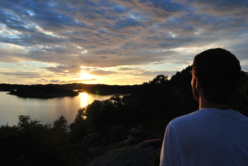 young man from behind looking at sunset
