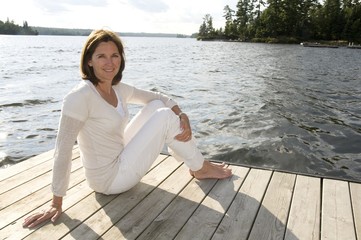 Woman Relaxing On Dock, Lake Of The Woods, Ontario, Canada