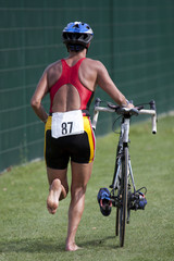 triathlète poussant son vélo en zone de transition