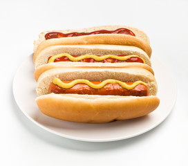 three classic hot dogs with mustard and ketchup on a plate
