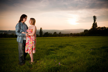 Young lovely couple flirt in mountain field on sunset