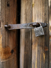 An old rusted padlock of a rural block house
