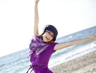 Portrait of red-haired girl with headphone on the beach.