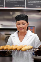 Cute young baker smelling baguettes